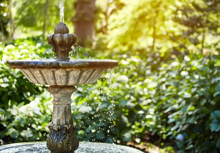 Ein antiker Gartenbrunnen sprudelt im Sonnenlicht. Tolle Ideen für Brunnen im Garten, die Ruhe und Schönheit bringen.