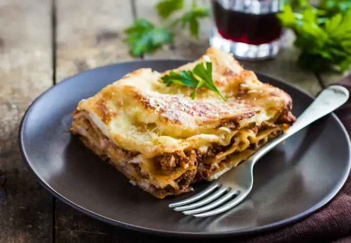 Pyszna lasagne z mielonym mięsem, idealna odpowiedź na pytanie: jakie mięso do lasagne. Podana na talerzu z widelcem.