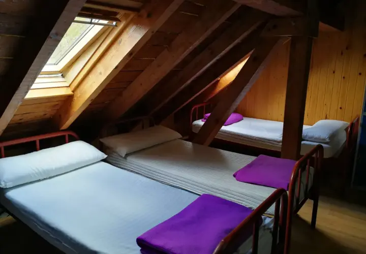Refugio con ángulos de madera y camas sencillas, listo para recibir a viajeros.