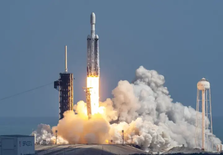 Rakieta Falcon Heavy SpaceX startuje, wzbijając się w niebo z potężnym płomieniem i kłębami dymu.