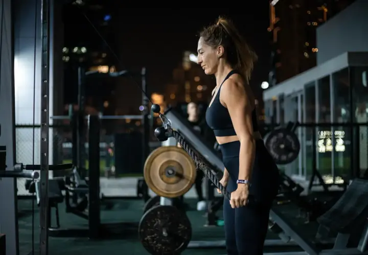Kobieta ćwiczy na siłowni nocą. Zastanawia się nad kartą multisport cena, by mieć dostęp do takich treningów.