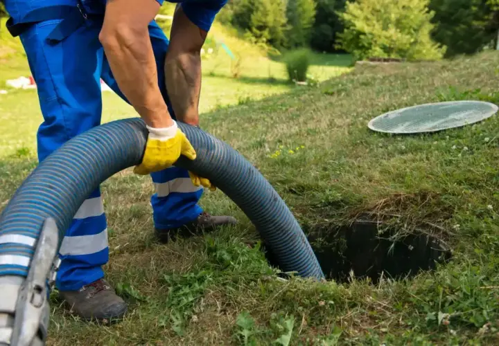 Pracownik w żółtych rękawicach obsługuje wąż do wywozu szamba. Sprawdź nasz wywóz szamba cennik i zadbaj o czystość.