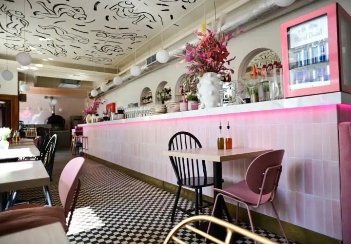 Stylowe wnętrze restauracji w Warszawie z różowym neonem i czarno-białą szachownicą na podłodze. Idealne miejsce na listę "top 10 restauracji Warszawa".