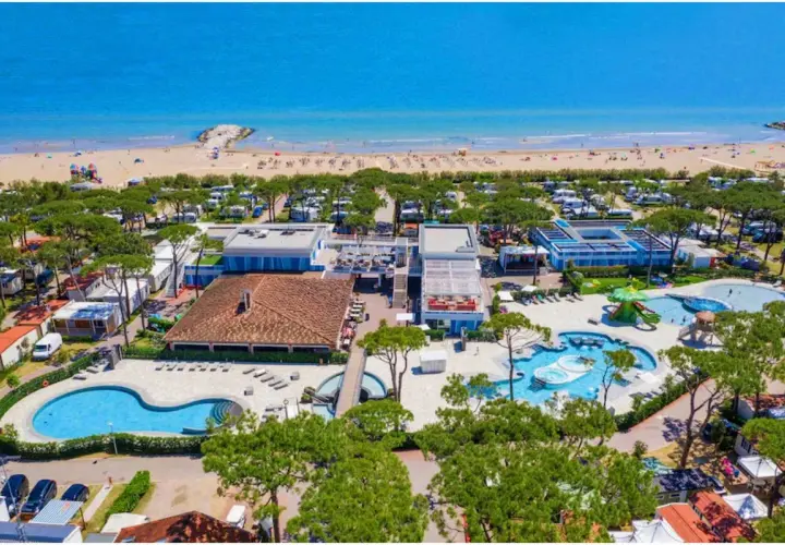 Vue aérienne d'un camping et d'une plage à Cavallino, Italie. Piscines, mobil-homes et mer bleue.