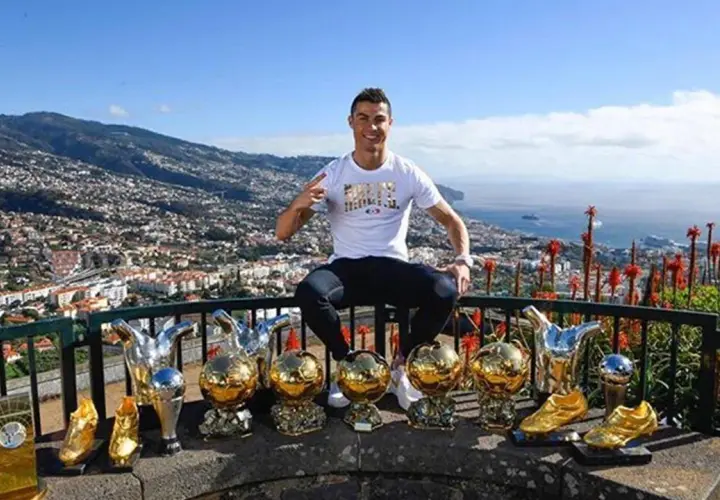 Cristiano Ronaldo z pięcioma złotymi piłkami, symbolizującymi jego sukcesy.
