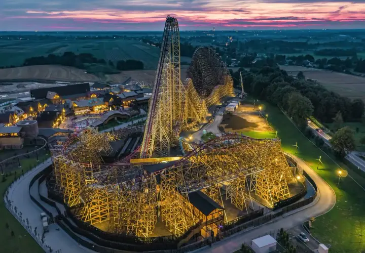 Drewniany gigant, największy rollercoaster w Europie, lśni w blasku nocnych świateł. Jego imponująca konstrukcja wznosi się ku niebu, zapraszając na niezapomnianą przygodę.