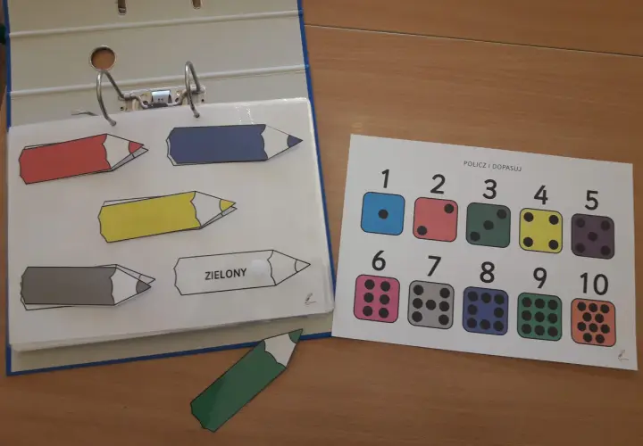 Kolorowe kredki i kostki do gry na karcie "Policz i dopasuj" to część edukacyjnych książeczek aktywizujących.