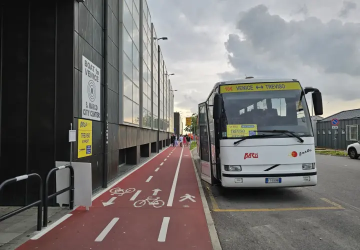 Autobus na lotnisku Treviso z napisem "Venice <-> Treviso". Czerwona ścieżka rowerowa i piesza obok budynku.