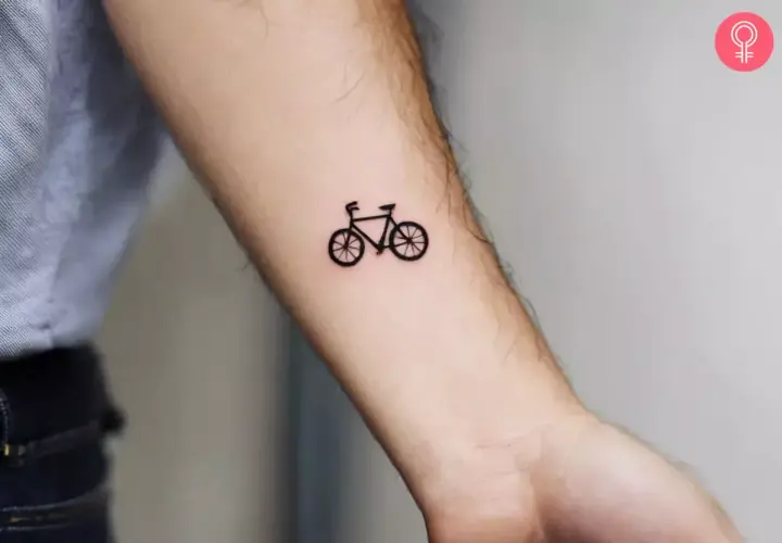 Minimalistyczny tatuaż rower szosowy na przedramieniu. Symbol wolności i pasji do podróży.