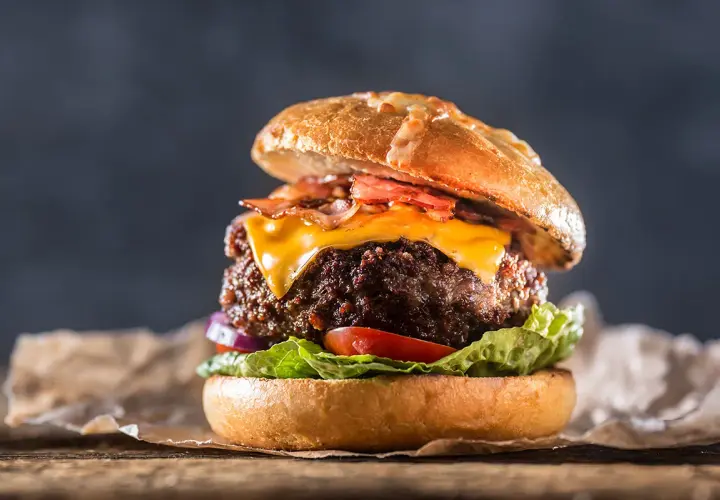 En saftig hamburgare med ost och bacon, perfekt för att grilla hamburgare en solig dag.