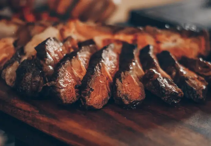 Tranches de viande juteuse sur une planche en bois. Idéal pour savoir quel vin servir avec une pierrade de viande.