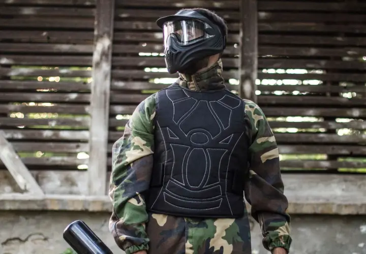 Gracz w kamizelce ochronnej i masce, gotowy do gry. Tak się ubiera na paintball, by czuć się bezpiecznie i komfortowo.