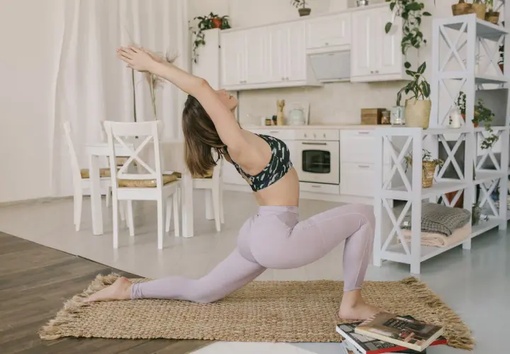 Kobieta w pozycji anjaneyasana rozciąga się w kuchni.