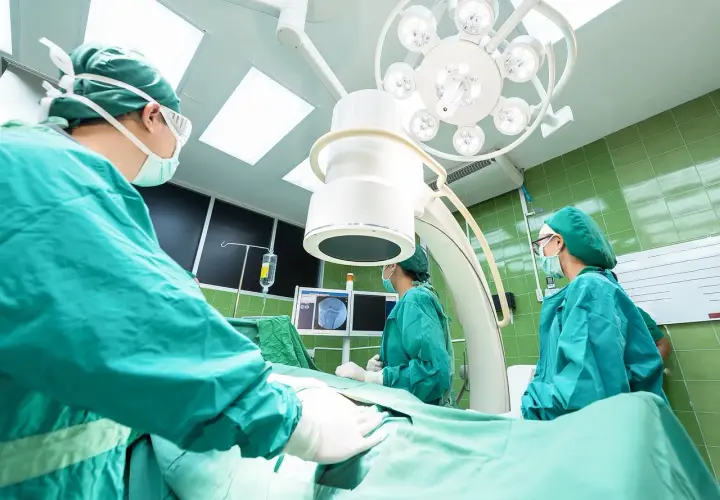 Chirurghi in sala operatoria, concentrati sul loro lavoro. La loro **responsabilità professionale** è evidente in ogni gesto.