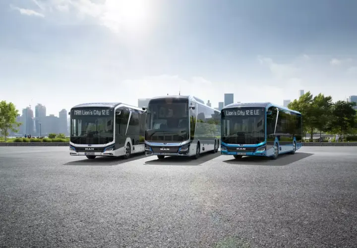 Trzy nowoczesne autobusy elektryczne MAN Lion's City E stoją na tle miejskiej panoramy.