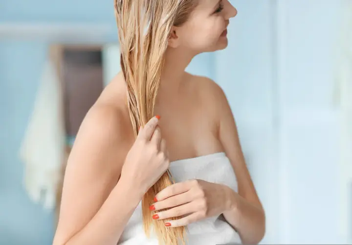 Kobieta z blond włosami nakłada domową odżywkę do włosów, która nadaje im blask i miękkość.
