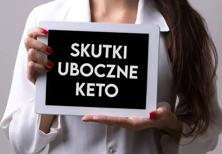 Kobieta trzyma tablet z napisem "SKUTKI UBOCZNE KETO". Zastanawiasz się nad dietą keto? Poznaj potencjalne skutki uboczne.
