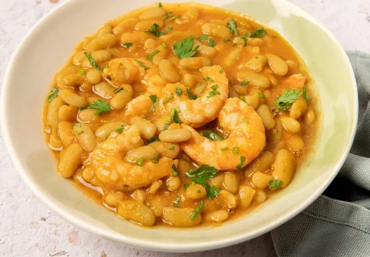 Plato de verdinas con langostinos, guisadas en una salsa sabrosa y adornadas con perejil fresco.