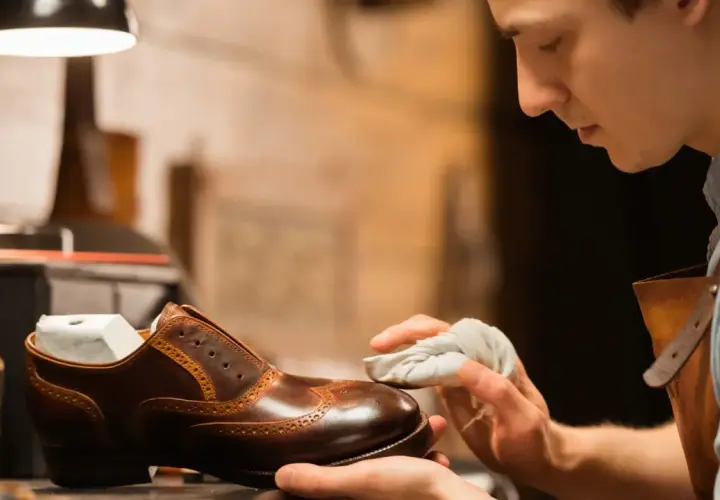 Un artisan applique du cirage pour chaussures sur un soulier en cuir marron, lui redonnant son éclat.