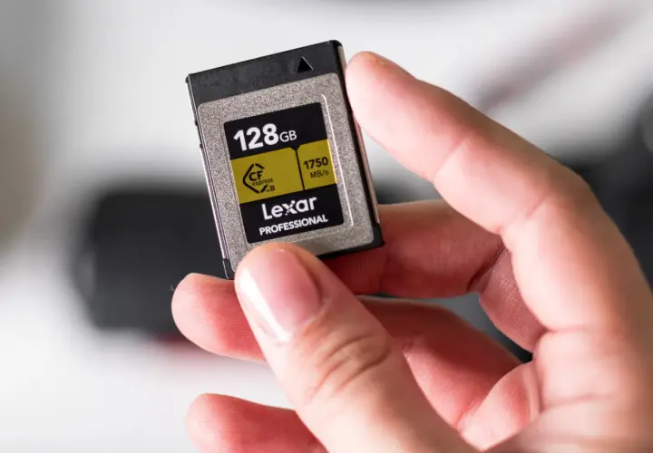 Dłoń trzyma kartę Lexar CFexpress B 128GB, jeden z zaawansowanych rodzajów kart pamięci dla profesjonalistów.