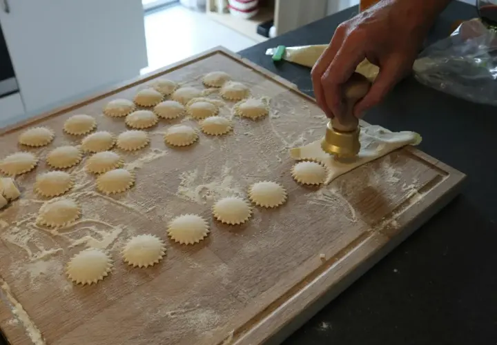 Ręcznie robione ravioli z pysznym farszem do ravioli, przygotowywane na drewnianej desce.