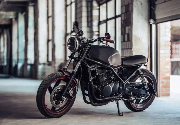 Elegante moto customizada, negra y con detalles rojos, lista para la aventura. Una moto sin papeles que inspira libertad y rebeldía.