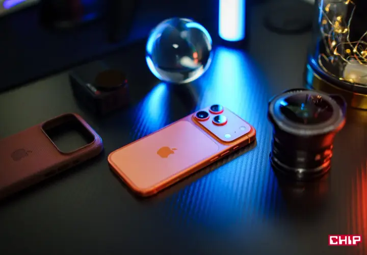 Pomarańczowy iPhone, skórzane etui i obiektyw na czarnym blacie. Idealna konfiguracja iPhone dla fotografa.