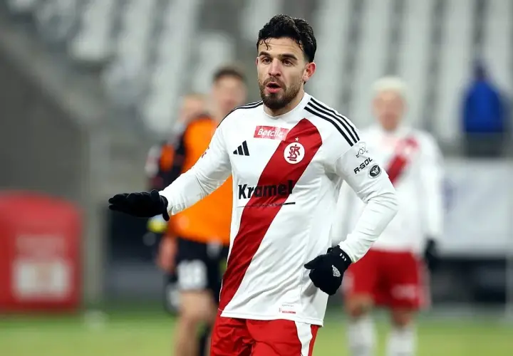 Piłkarz Stali Mielec w białej koszulce z czerwonym pasem, gotowy do gry przeciwko ŁKS Łódź.