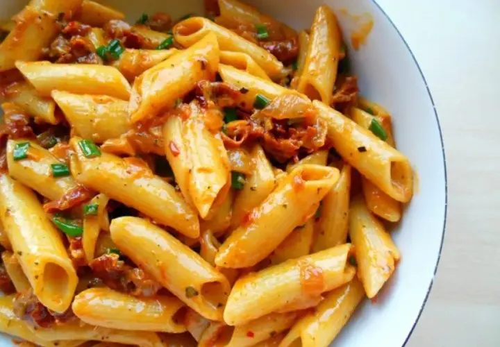 Penne z sosem z suszonych pomidorów i zieloną cebulką, apetyczne danie pełne smaku.