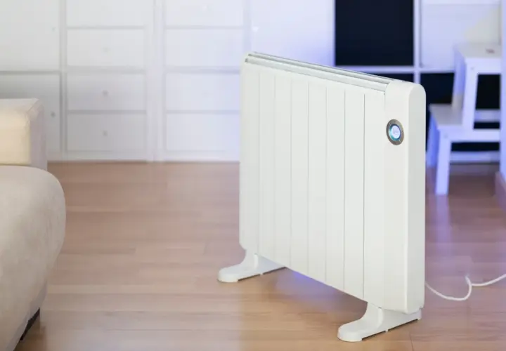 Calentador blanco emitiendo un suave calor azul. Un sofá beige y armarios blancos completan la escena.