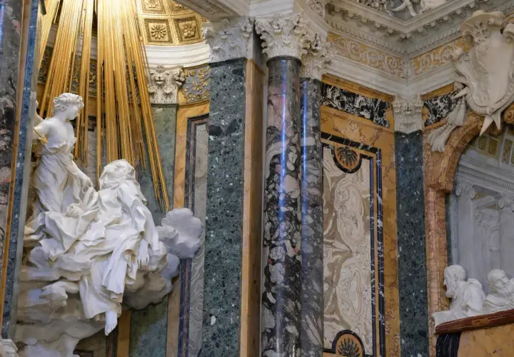 La Cappella Cornaro: un angelo colpisce Santa Teresa con una freccia dorata, circondata da marmi preziosi e decorazioni barocche.