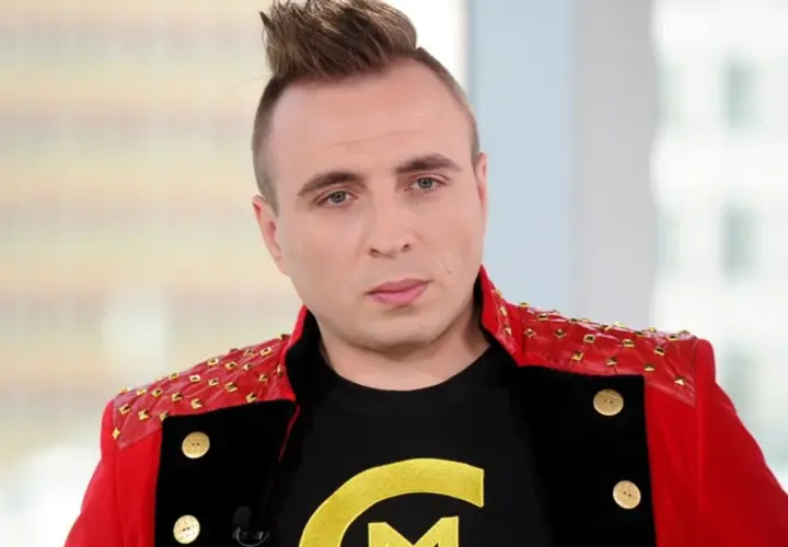 Czadomen w czerwonej marynarce z ćwiekami i czarnej koszulce z żółtym logo.