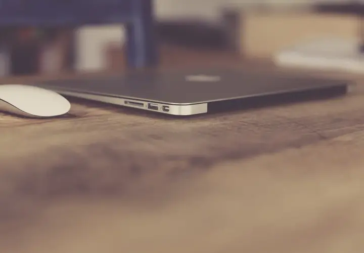 Elegancki, zamknięty laptop biznesowy i biała myszka na drewnianym biurku. Idealny zestaw do pracy.