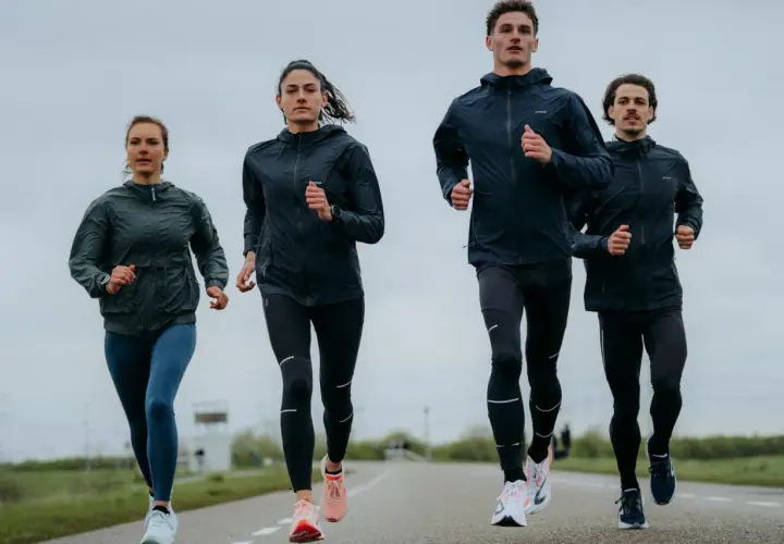 Cztery osoby biegną po drodze, ubrani w sportowe kurtki i legginsy. Wyglądają, jakby właśnie odkryli, kiedy wynaleziono bieganie.