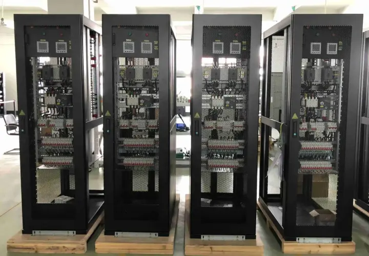 Cuatro racks negros con equipos electrónicos visibles a través de rejillas, parte de un cuarto de comunicaciones.
