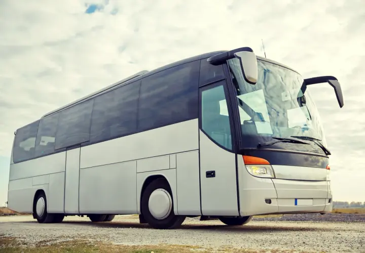 Biały autokar turystyczny na tle nieba z chmurami.