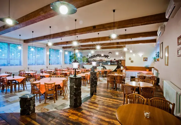 Szukasz miejsca, gdzie zjeść w Mielnie? Przytulna restauracja z drewnianymi belkami i stołami nakrytymi pomarańczowymi obrusami zaprasza.