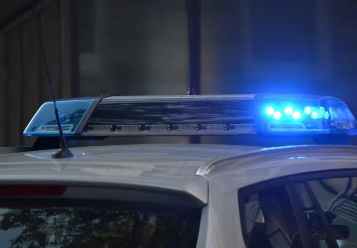 Niebieskie światła pojazdu uprzywilejowanego migają na dachu radiowozu.