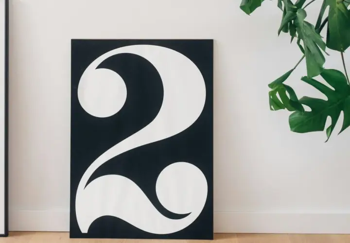 Póster minimalista con el número 2 en blanco sobre fondo negro, evocando su 2 significado espiritual. Una planta verde decora la escena.