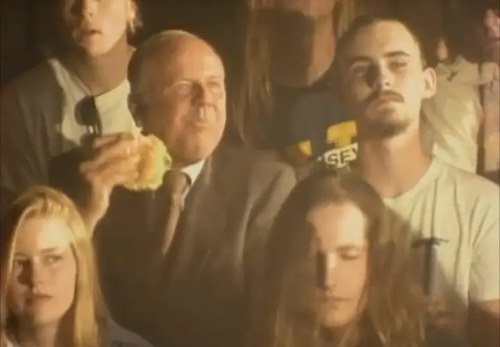 Tłum ludzi, wśród nich starszy mężczyzna jedzący burgera. Atmosfera jest mroczna, ale czuć w niej energię, jakby to był koncert, który pachnie nirwaną.