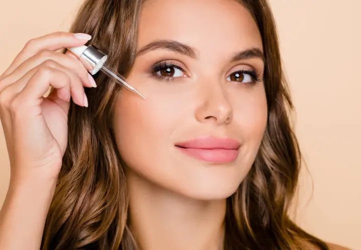 Kobieta aplikuje serum z pipetką, rozpoczynając swoją kurację retinolem dla promiennej cery.