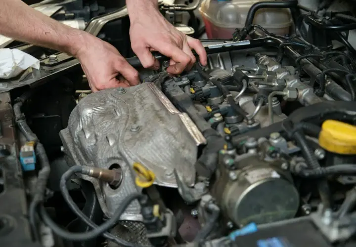 Mechanik pracuje przy silniku, sprawdzając czujnik położenia wałka rozrządu. Objawy awarii mogą być różne, od nierównej pracy po problemy z odpaleniem.