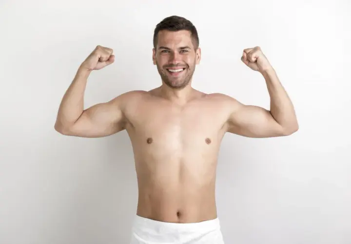 Uśmiechnięty mężczyzna prezentuje swoją szewską klatkę piersiową, napinając bicepsy.