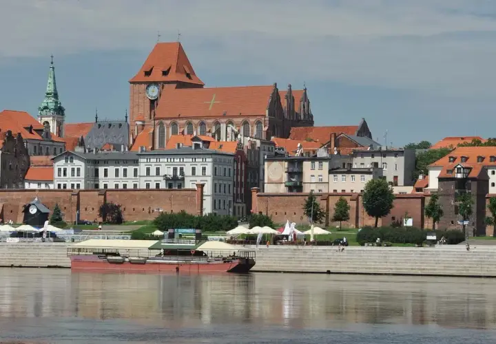 Widok na średniowieczny zespół miejski Torunia z Wisły. Widać katedrę, mury obronne i kamienice.