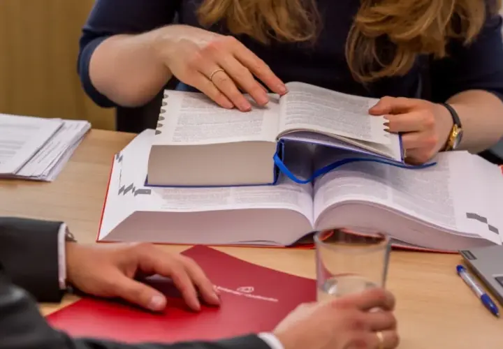 Dwie osoby analizują przepisy prawne dotyczące najmu i przedawnienia. Na stole dokumenty, książki i szklanka wody.