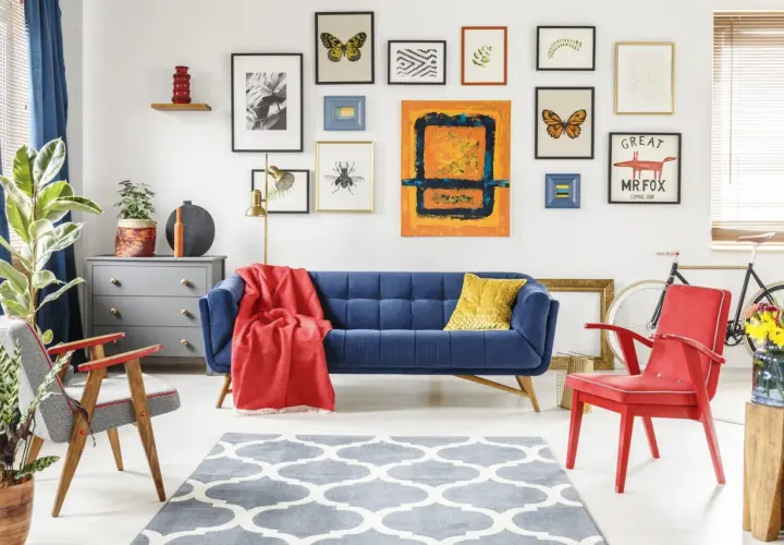 Przytulny pokój w stylu vintage z niebieską kanapą, czerwonym fotelem i galerią obrazów na ścianie.