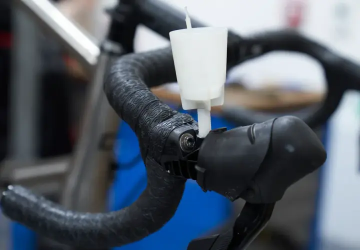 A white funnel attached to a bicycle handlebar, part of an easy way to bleed brakes.