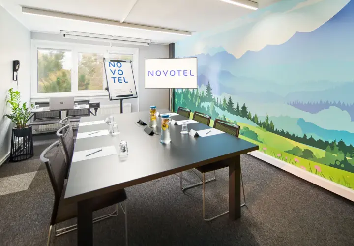 Nowoczesna sala konferencyjna Novotel z malowniczą wizualizacją dla dorosłych na ścianie.