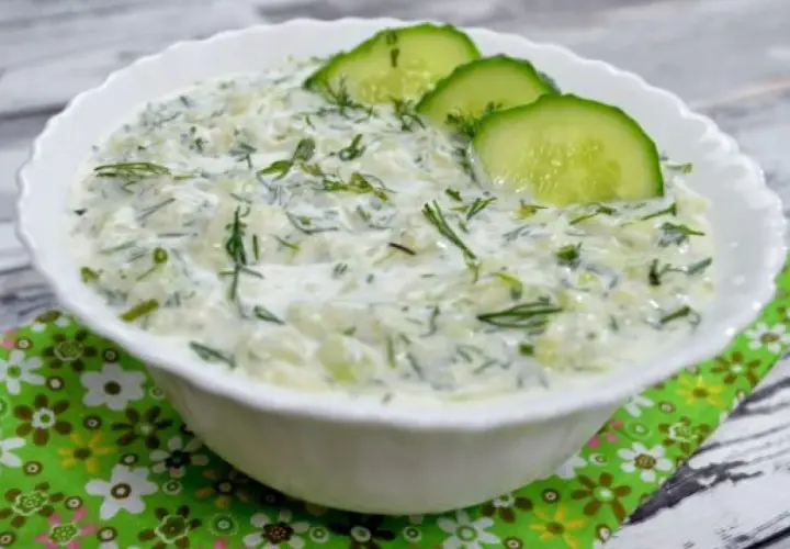 Pyszny, kremowy sos tzatziki z kawałkami ogórka i świeżym koperkiem, ozdobiony plasterkami ogórka. Idealny dodatek do greckich potraw.
