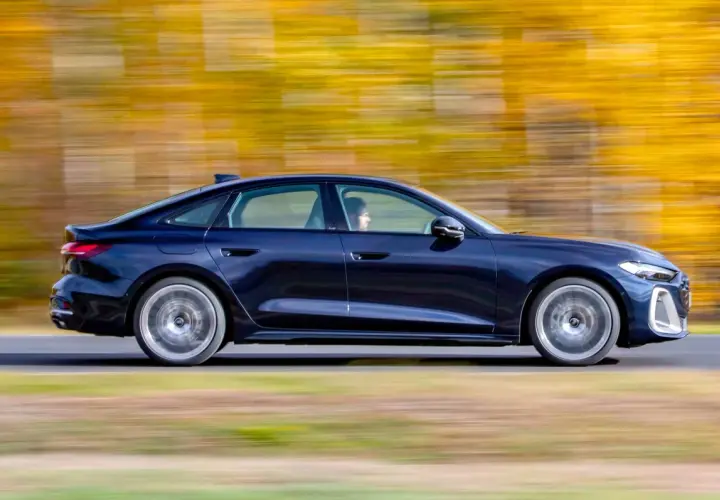 Ciemnoniebieskie Audi A4 B10 w ruchu, z rozmytym jesiennym tłem.